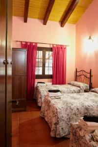 1 dormitorio con 3 camas y cortinas rojas en casa rio alberche y el cortijo de gredos, en Navaluenga