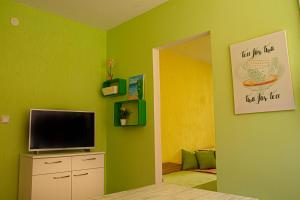 Апартамент Морски Полъх في رافدا: غرفة نوم بجدران خضراء وتلفزيون على خزانة
