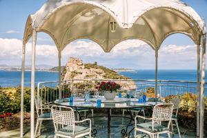 einen Pavillon mit einem Tisch, Stühlen und Meerblick in der Unterkunft Villa Livia in Ischia