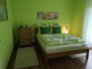 ein Schlafzimmer mit einem Bett mit grünen Wänden und einem Nachttisch in der Unterkunft Ninas B&B - exklusiv für Frauen in Bremen