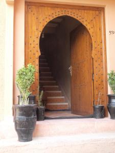 a stairway with a wooden door and potted plants at Maison d'Hôtes Ghalil in Ouarzazate