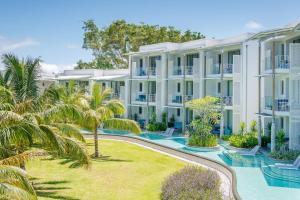 an exterior view of a large apartment building with a yard at Victoria Beachcomber Resort & Spa - Victoria for 2 - Adults Only in Pointe aux Piments
