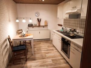 - une cuisine avec des placards blancs, une table et une cuisinière dans l'établissement Ferienwohnung Kasper, à Bad Bederkesa