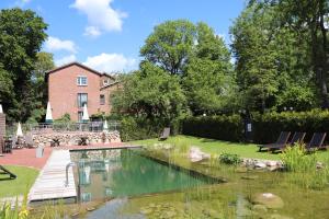 a garden with a pond in front of a house at Gasthof Oldenwöhrden in Wöhrden