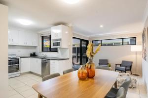 a kitchen and dining room with a wooden table at Indah - Lennox Head in Lennox Head