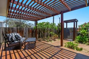 a wooden pergola with a bench on a deck at Indah - Lennox Head in Lennox Head