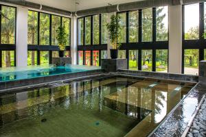 a pool in a building with glass windows at Oxigén Family Hotel Noszvaj in Noszvaj