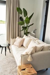 uma sala de estar com um sofá e um vaso de plantas em B&B Ganzendiep aan het water em Grafhorst