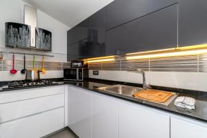 a kitchen with white cabinets and a stainless steel sink at Sunset Bay Tecno Home Sardinia in Valledoria