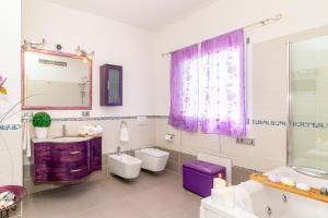 een badkamer met 2 toiletten, een wastafel en een spiegel bij Sunset Bay Tecno Home Sardinia in Valledoria
