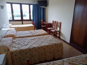 a hotel room with three beds and a desk at Hotel Costa Cántabra in Argoños