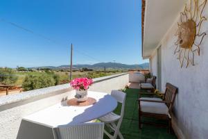 een balkon met een tafel en stoelen en een vaas met bloemen bij Sunset Bay Tecno Home Sardinia in Valledoria