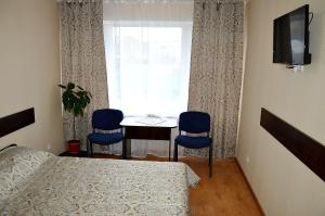 a bedroom with a bed and two chairs and a window at Готель Профспілковий in Vinnytsya