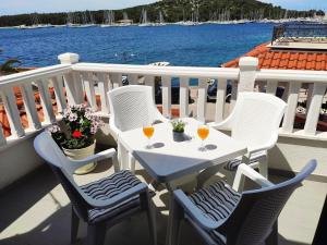 a white table and chairs on a balcony with the water at Apartman Marina II in Rogoznica