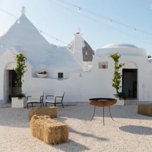 a white building with chairs and a table in front of it at Petranima Wellness in Trulli in Ostuni