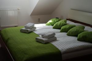a large bed with green pillows and towels on it at Pivovarský Hotel in Kojetín