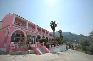 a pink house with a palm tree in front of it at Pink Palace Beach Resort in Agios Gordios