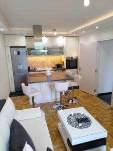 a living room with a white couch and a kitchen at Ana Apartment in Novi Sad