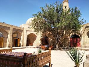 a bench in front of a building with a tree at Caravan Sarai in Khiva