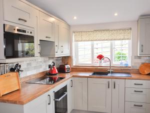 a kitchen with white cabinets and a sink and a window at Hafan in Llanerfyl