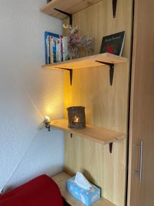 ein Regal mit einer Kerze und einer Schachtel darauf. in der Unterkunft Sunny Swiss mountain Studio in centre by Jolidi in Nendaz
