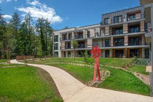 un bâtiment avec une fleur rouge dans l'herbe dans l'établissement Résidence Les Tisserands - Domitys, à Beauvais