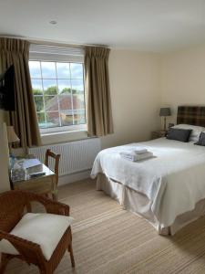 a bedroom with a bed and a chair and a window at Devonia Guest House in Lyme Regis