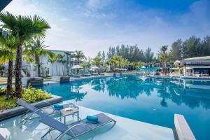 einen Pool in einem Resort mit Stühlen und Palmen in der Unterkunft The Waters Khao Lak by Katathani - SHA Extra Plus in Khao Lak
