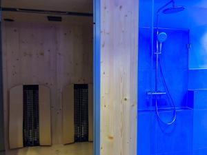 ein Bad mit einer Dusche und einer blauen Wand in der Unterkunft das Luggi Appartements in Reith im Alpbachtal