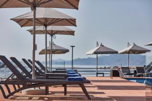 una fila di sedie a sdraio e ombrelloni in piscina di ALKINOI RESORT AND SPA a Monemvasía