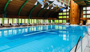 a large swimming pool with chairs in a building at Spa Residence Carbona Apartman 104 in Hévíz