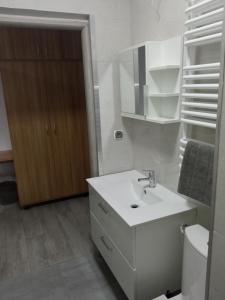 Baño blanco con lavabo y aseo en Szafir - NoclegiGrodziskPL, en Grodzisk Mazowiecki