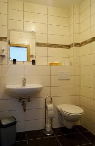 Hotel zur Post في باشاراش: حمام مع حوض ومرحاض ومرآة
