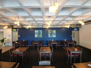 a dining room with tables and chairs and a blue wall at Citrus Hotel Cardiff by Compass Hospitality in Cardiff