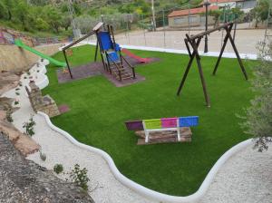 a park with a playground with a bench and swings at Casa Serrana in Santa Cruz de Moya