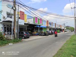 a person riding a motorcycle down a street with buildings at Comfy Emerald Hill Karawang in Telukjambe