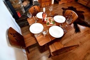 d'une table en bois avec des assiettes et des verres à vin. dans l'établissement Apartamenty Rogowcówka, à Biały Dunajec