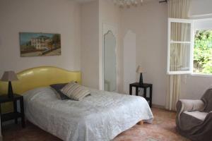 a bedroom with a bed and a chair and a window at Grande maison au cadre verdoyant au centre village in Cargèse