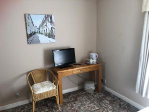 Zimmer mit einem Schreibtisch, einem TV und einem Stuhl in der Unterkunft Fairview Bed and Breakfast in Airdrie