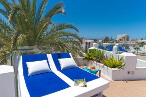 a blue and white bed on a balcony with a palm tree at Alsol Los Caribes 2 - Adults Only in Playa del Ingles