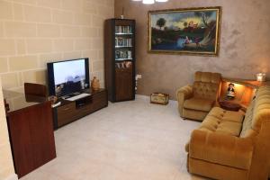 un soggiorno con TV, divano e sedie di Grazzja Traditional Apartment a Żabbar