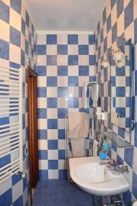 uma casa de banho com paredes em azulejos azuis e brancos e um lavatório. em Le Soleil B&B em Milazzo