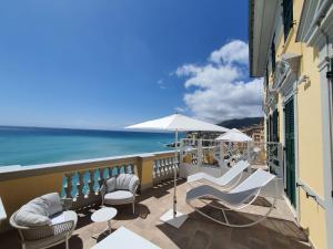 a balcony with chairs and an umbrella and the ocean at Sublimis Boutique Hotel Adults-Only in Camogli