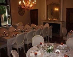 une salle à manger avec des tables et des chaises ainsi qu'un lustre dans l'établissement Chateau De Charge, à Razines