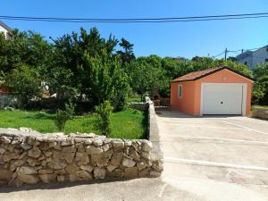 a garage with a stone wall next to a building at Apartmani Jašarević in Martinšćica