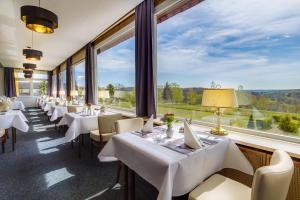 ein Restaurant mit weißen Tischen und Stühlen und großen Fenstern in der Unterkunft Panorama Ferien Hotel Harz in Güntersberge