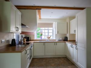 kuchnia z białymi szafkami i oknem w obiekcie Prince Rupert w mieście Winchcombe