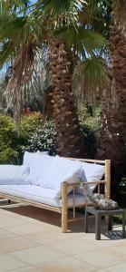 a white couch sitting in front of a palm tree at studio 5min plage agosta in Albitreccia