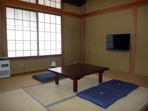 een woonkamer met een tafel en een televisie bij K's House Hakuba Alps - Travelers Hostel in Hakuba