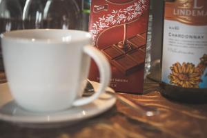 The Dragonfly في ستورنووي: كوب قهوة أبيض على طبق بجوار زجاجة من النبيذ